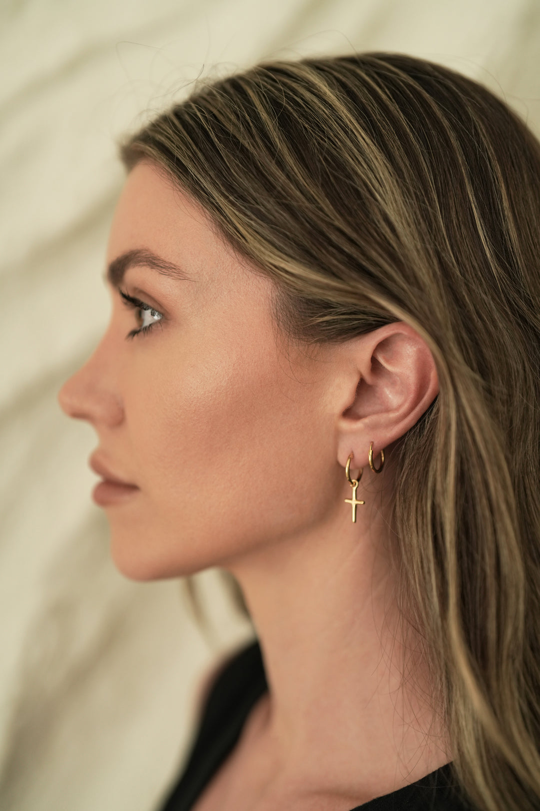 Founder of Nusands Emily Micari side profile wearing the 18K Gold cross earrings