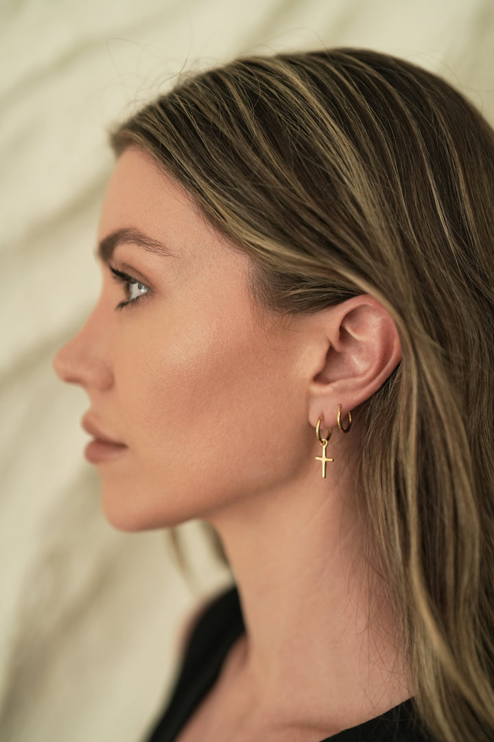 Founder of Nusands Emily Micari side profile wearing the 18K Gold cross earrings