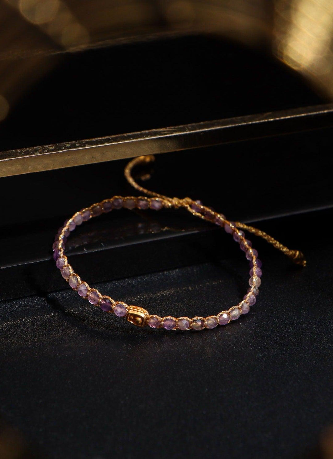 Purple beaded bracelet on a dark surface with a blurred background