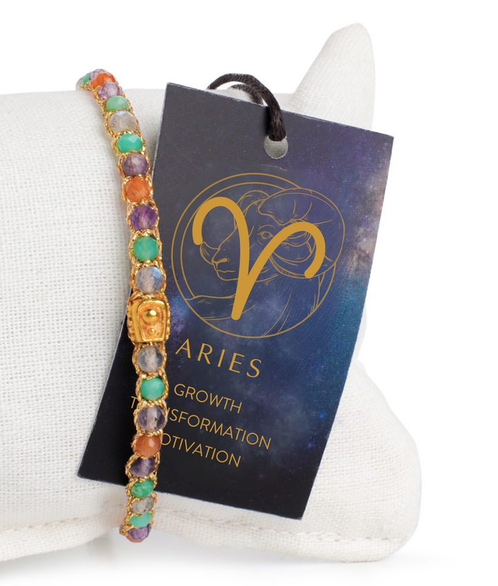 Multicolored gemstone bracelet on a stand with an Aries zodiac card