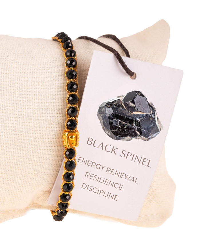 Black spinel bracelet on a white background with a card describing its properties.