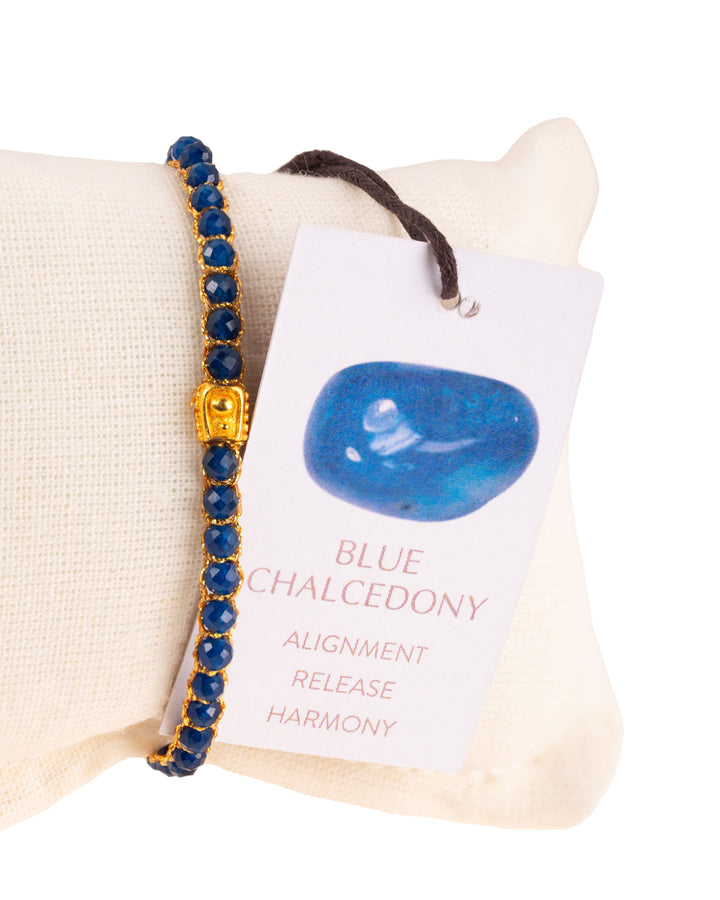 Blue Chalcedony Gemstone Adjustable bracelet covering white cushion strung together with 18K Gold Yarn, Information tag showing.