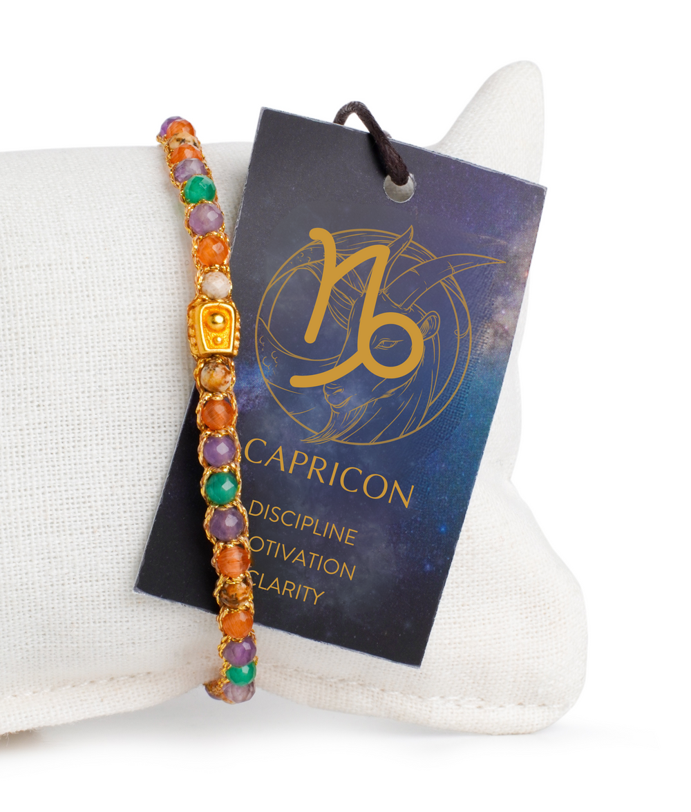 Multicolored beaded bracelet on a white cushion with a Capricorn zodiac card.