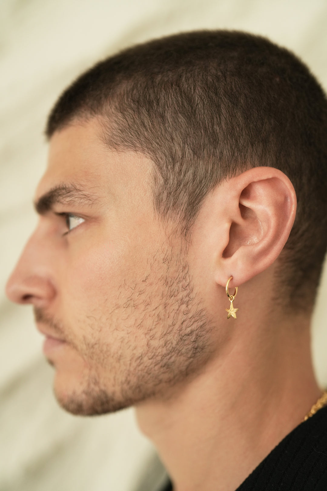 Founder of Nusands Corey Micari side profile wearing 18k gold round hoop earring with removable star charms.