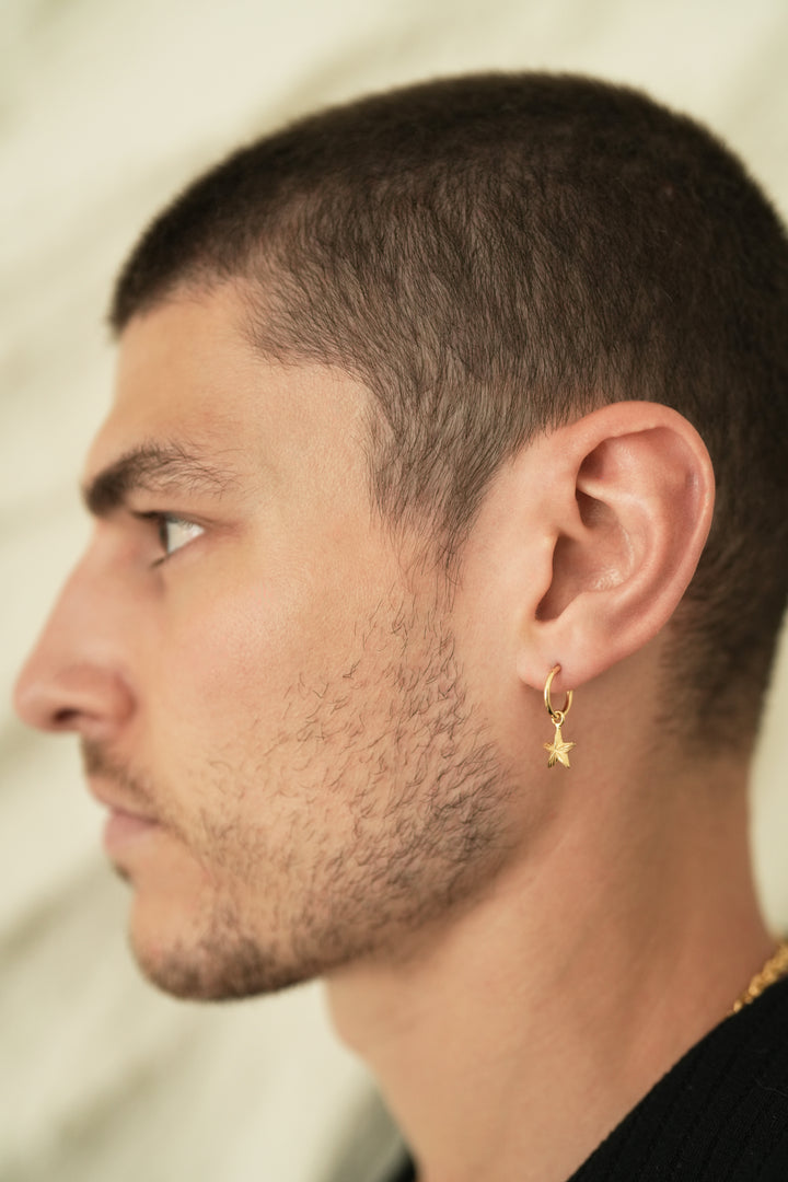 Founder of Nusands Corey Micari side profile wearing 18k gold round hoop earring with removable star charms.
