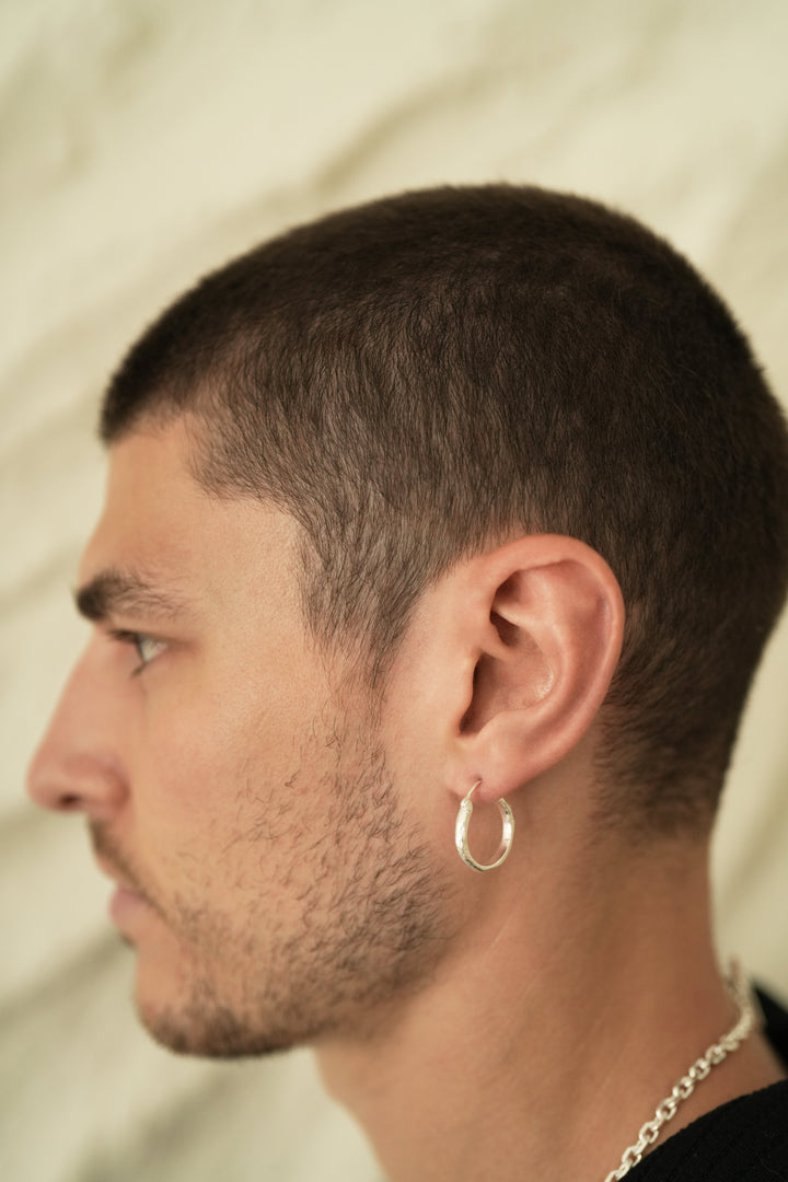 Founder of Nusands Corey Micari side profile wearing sterling silver wave earring in left ear.