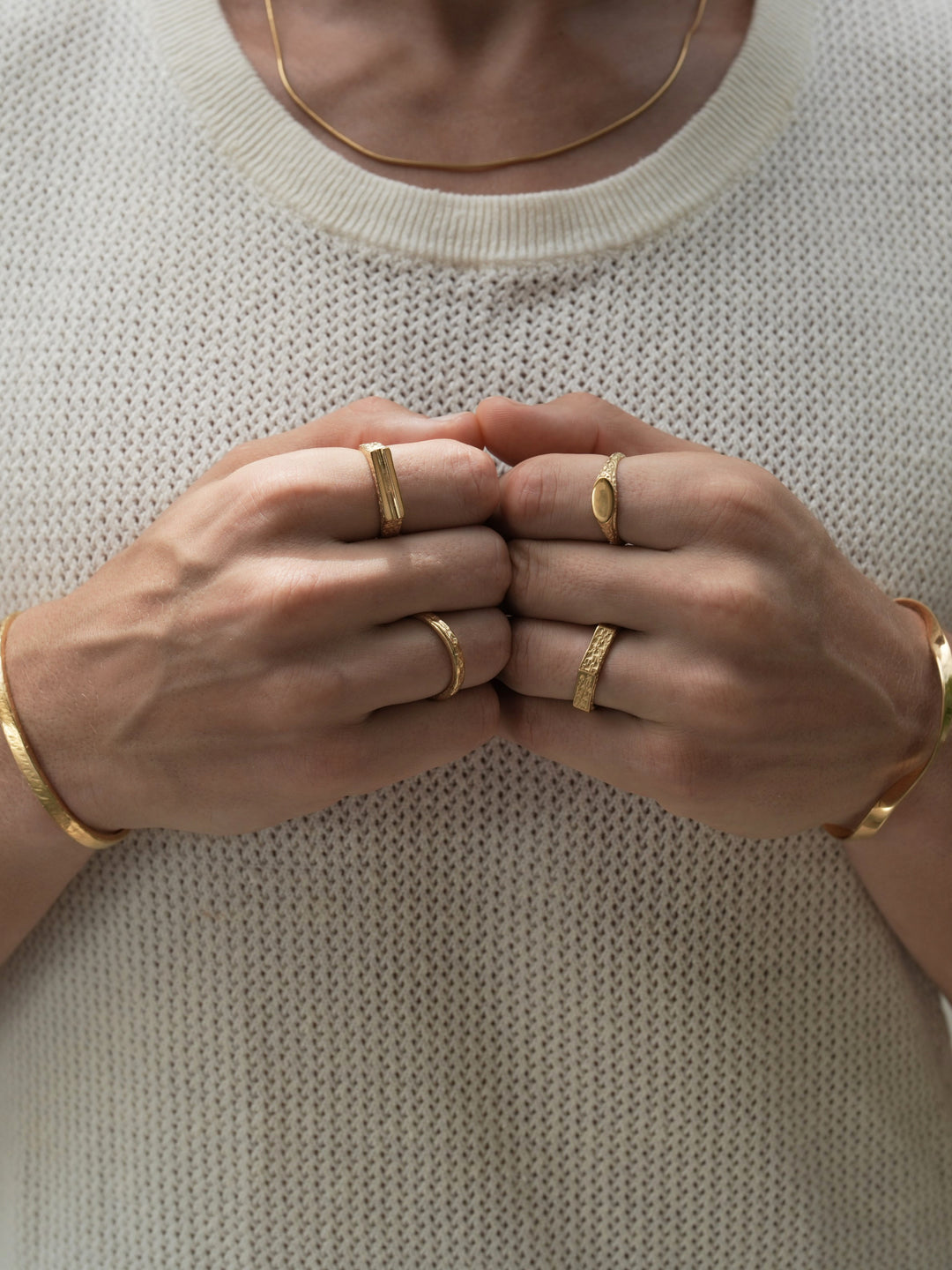 Founder of Nusands Corey Micari wearing 18k gold roped in necklace right hand with stirking cuff, line in the sand and stacker ring. Modest cuff on left wrist, mirrored signet and six base ring on hand fists together front profile