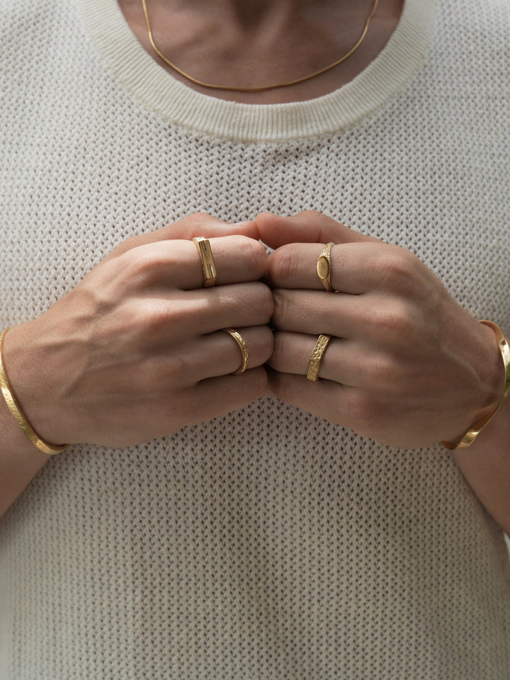 Founder of Nusands Corey Micari wearing 18k gold roped in necklace right hand with stirking cuff, line in the sand and stacker ring. Modest cuff on left wrist, mirrored signet and six base ring on hand fists together front profile