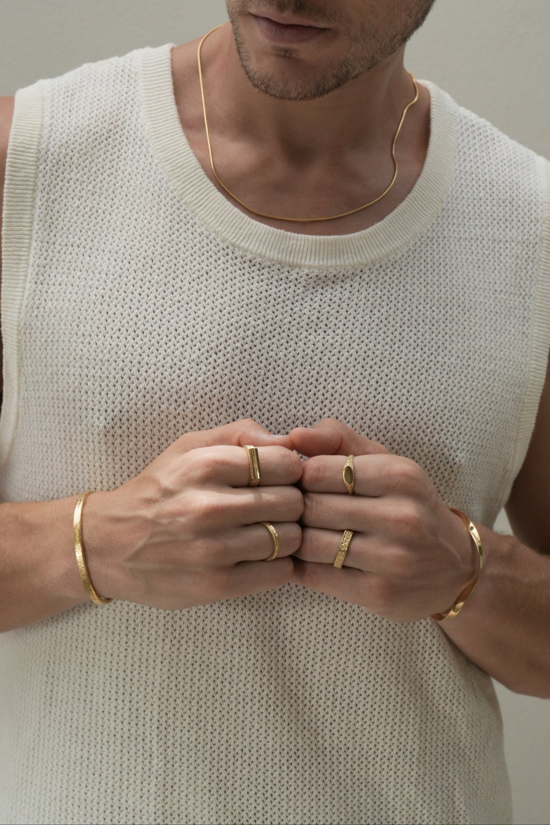 Founder of Nusands Corey Micari wearing 18k gold roped in necklace right hand with stirking cuff, line in the sand and stacker ring. Modest cuff on left wrist, mirrored signet and six base ring on hand fists together front profile