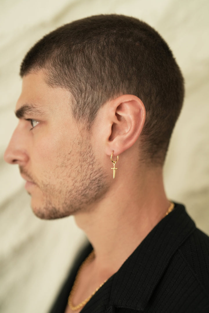 Founder of Nusands Corey Micari side profile wearing 18k gold hoop earrings with removable sword charms in left ear