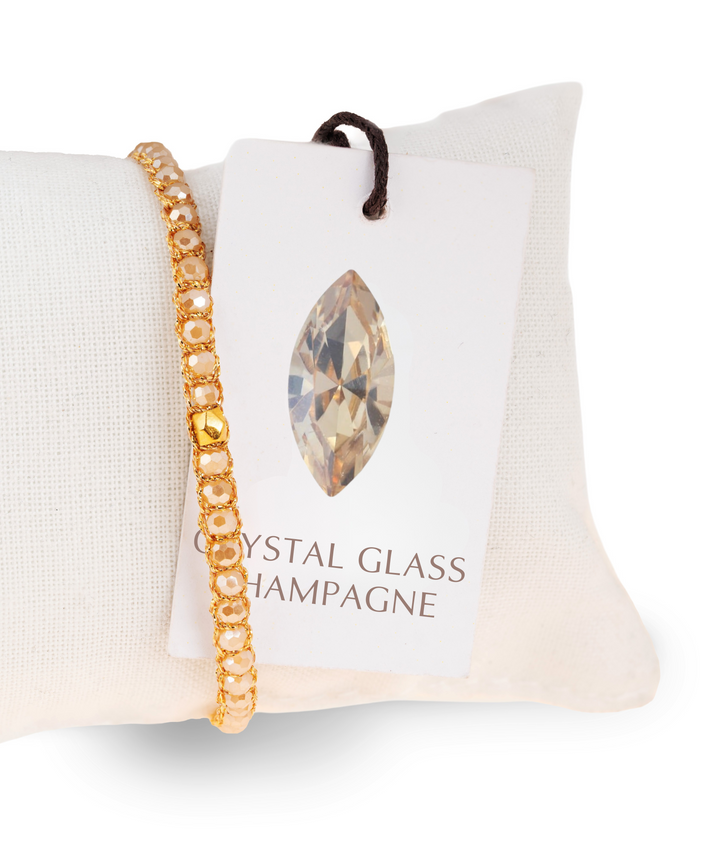 Gold bracelet with a crystal glass charm on a branded cushion