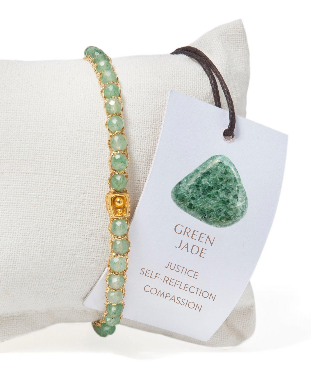 Green jade bracelet on a white cushion with a tag indicating its properties.