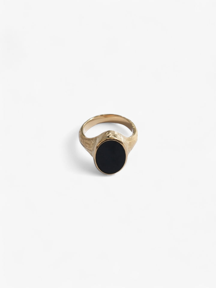 Nusands Midnight Onyx Ring in 18K Gold laying flat front on view. Oval shaped top with flat black onyx stone as a feature.