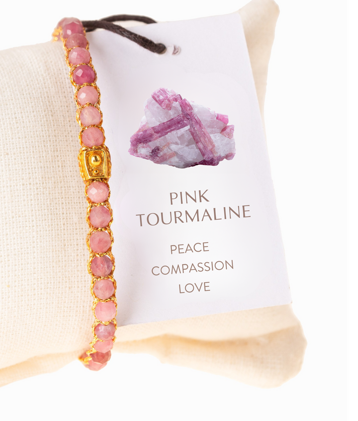 Pink tourmaline bracelet with gold accents on a white card with text and pink crystal image.