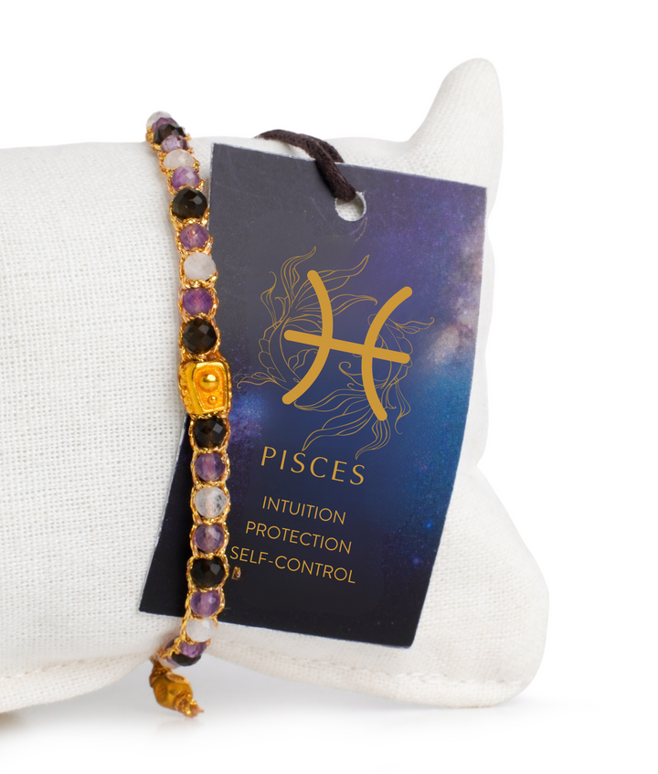 Bracelet with gemstones on a stand next to a Pisces zodiac card