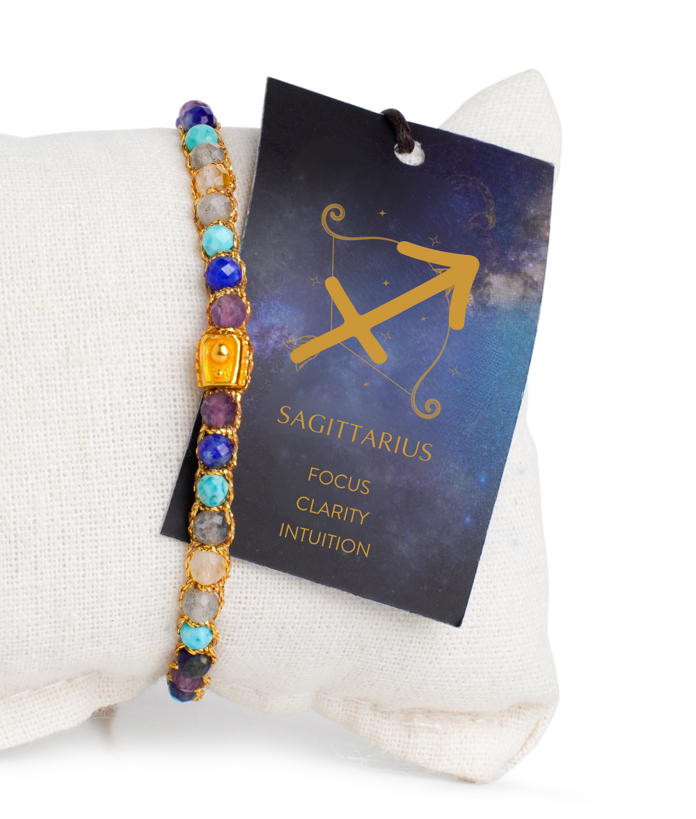 Colorful beaded bracelet with a Sagittarius zodiac sign tag on a white pillow.