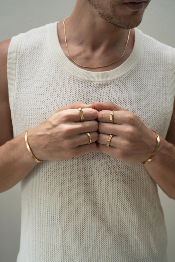 Founder of Nusands Corey Micari wearing 18k gold roped in necklace right hand with stirking cuff, line in the sand and stacker ring. Modest cuff on left wrist, mirrored signet and six base ring on hand fists together front profile
