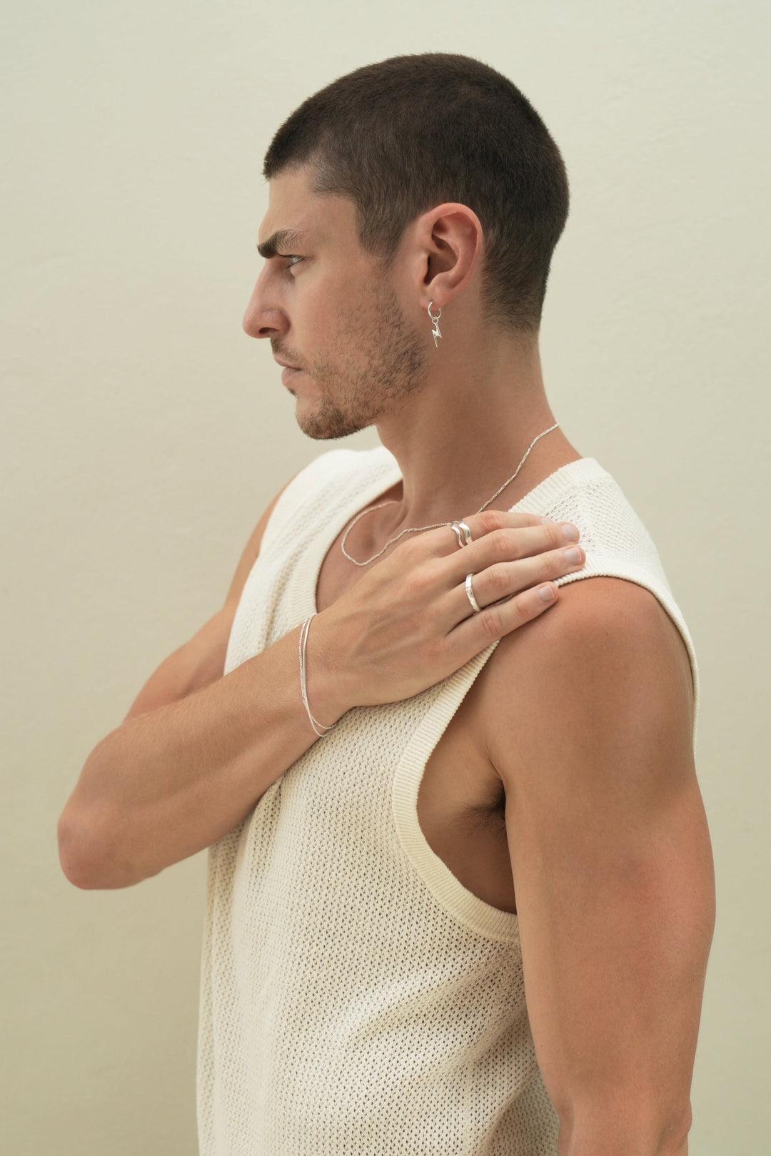 Founder of Nusands Corey Micari side profile wearing a range of sterling silver  bracelets, rings and necklace with a focus on lightning bolt earring
