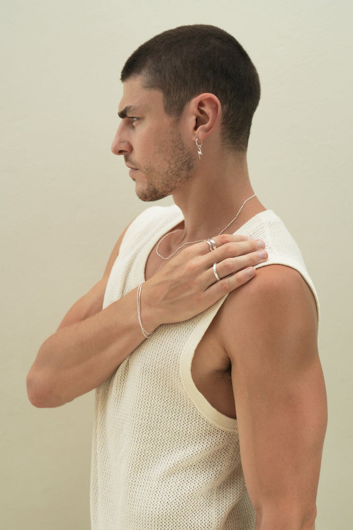 Founder of Nusands Corey Micari side profile wearing a range of sterling silver  bracelets, rings and necklace with a focus on lightning bolt earring