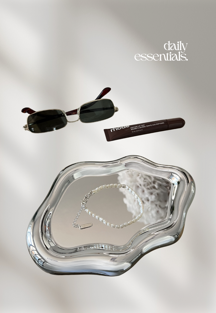 Nusands pearl bracelet on a silver tray with sunglasses and a rhode lip peptide 