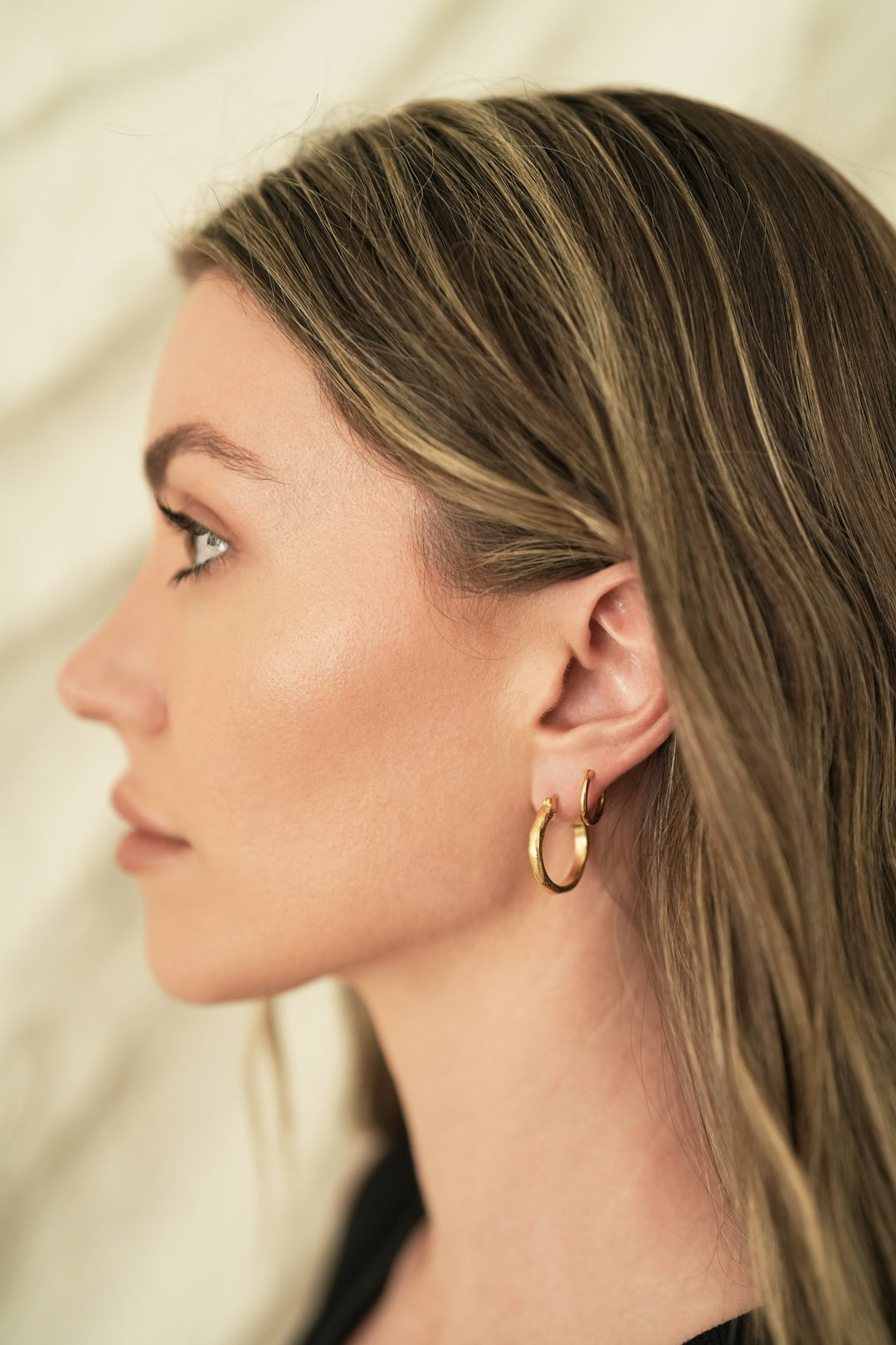 Founder of Nusands Emily Micari side profile wearing 18k gold wave earring in left ear.