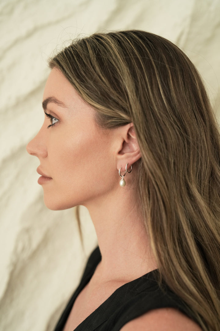 Founder of Nusands Emily Micari side profile wearing sterling silver hoop earrings with removable pearl charms.