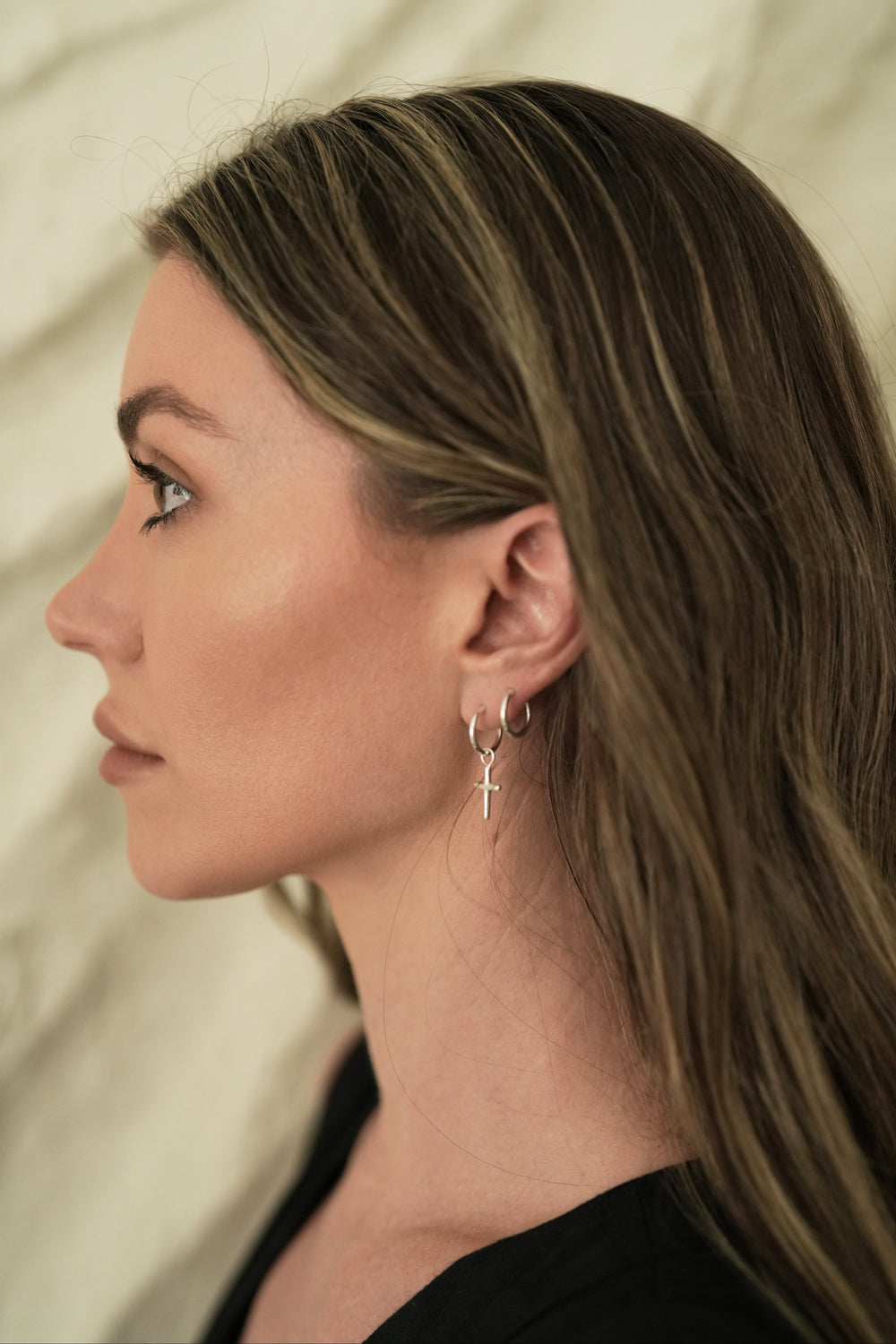 Founder of Nusands Emily Micar side profile wearing the sterling silver cross earrings