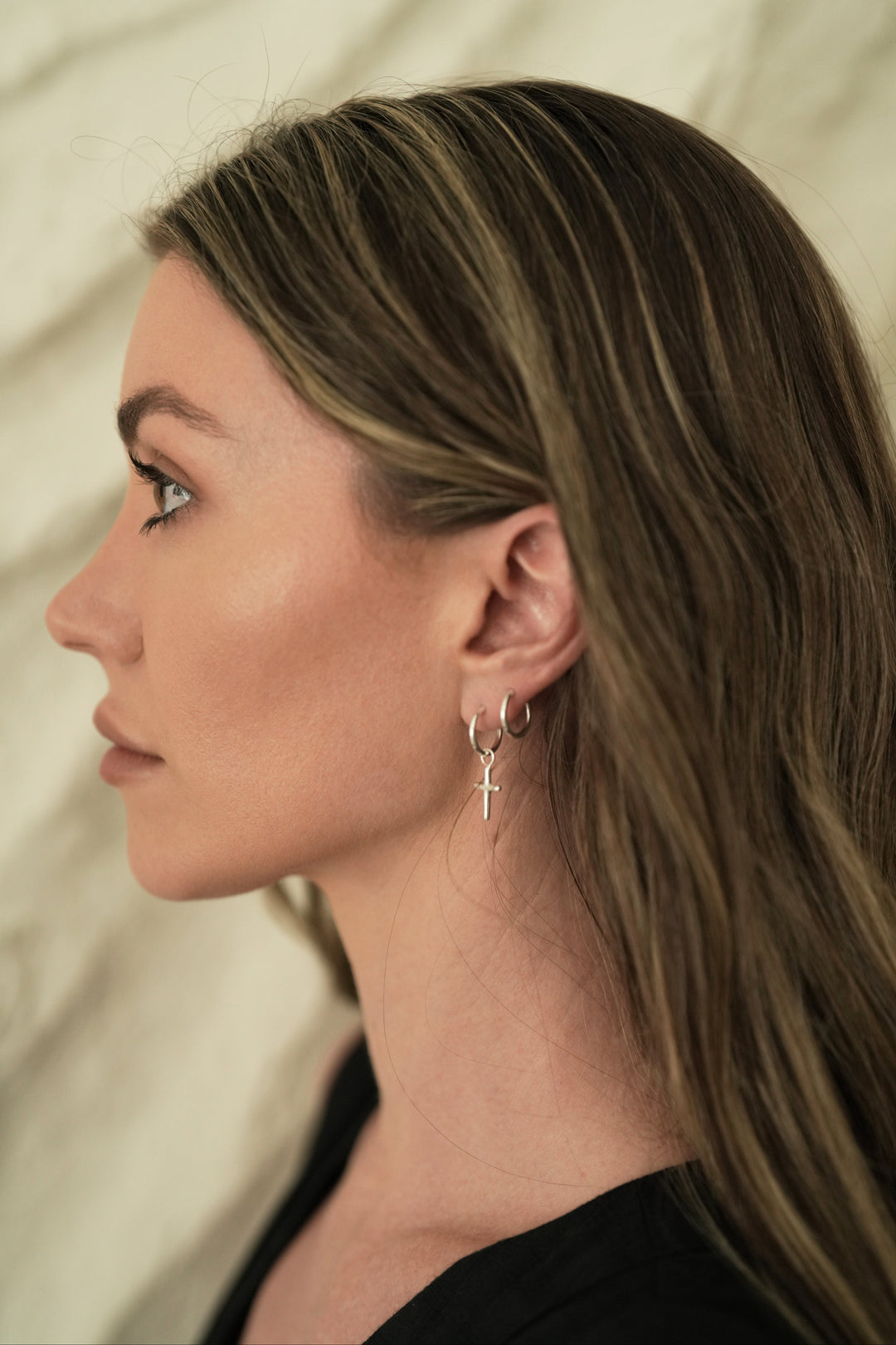 Founder of Nusands Emily Micar side profile wearing the sterling silver cross earrings