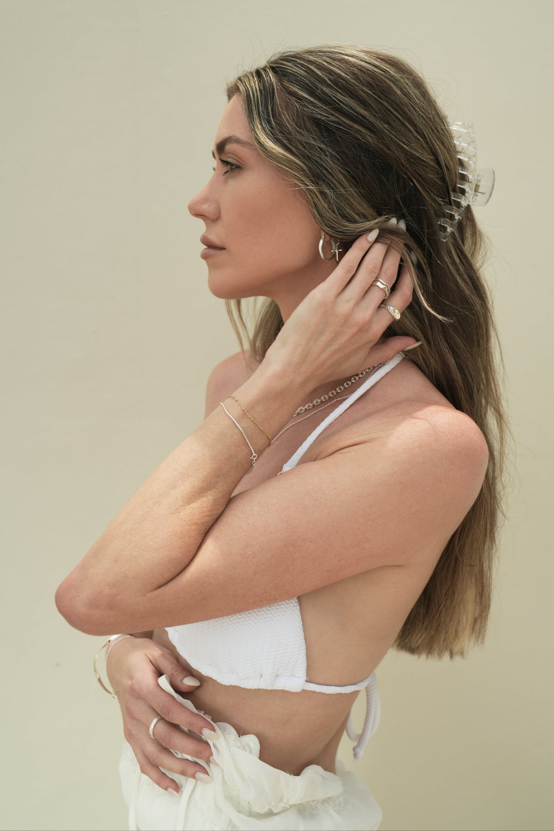 Founder of Nusands Emily Micari side profile wearing sterling silver bracelets, cuff, rings and cross earrings