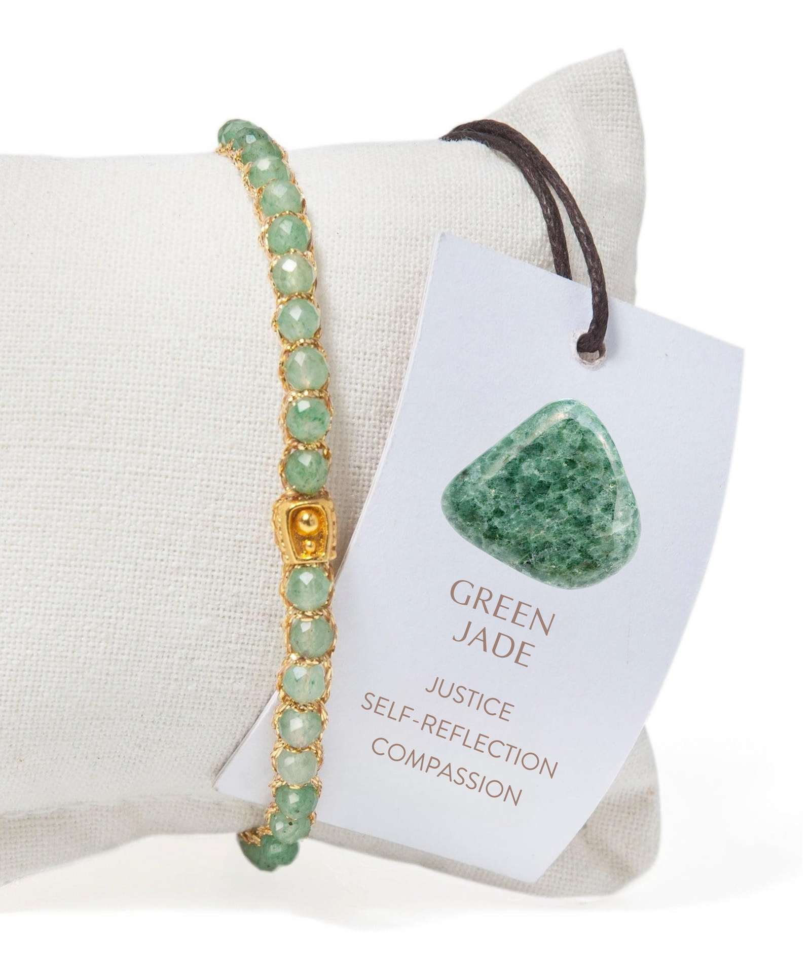 Green jade bracelet on a white cushion with a tag indicating its properties.