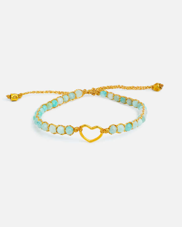 Turquoise beaded bracelet with gold heart charm on a white background