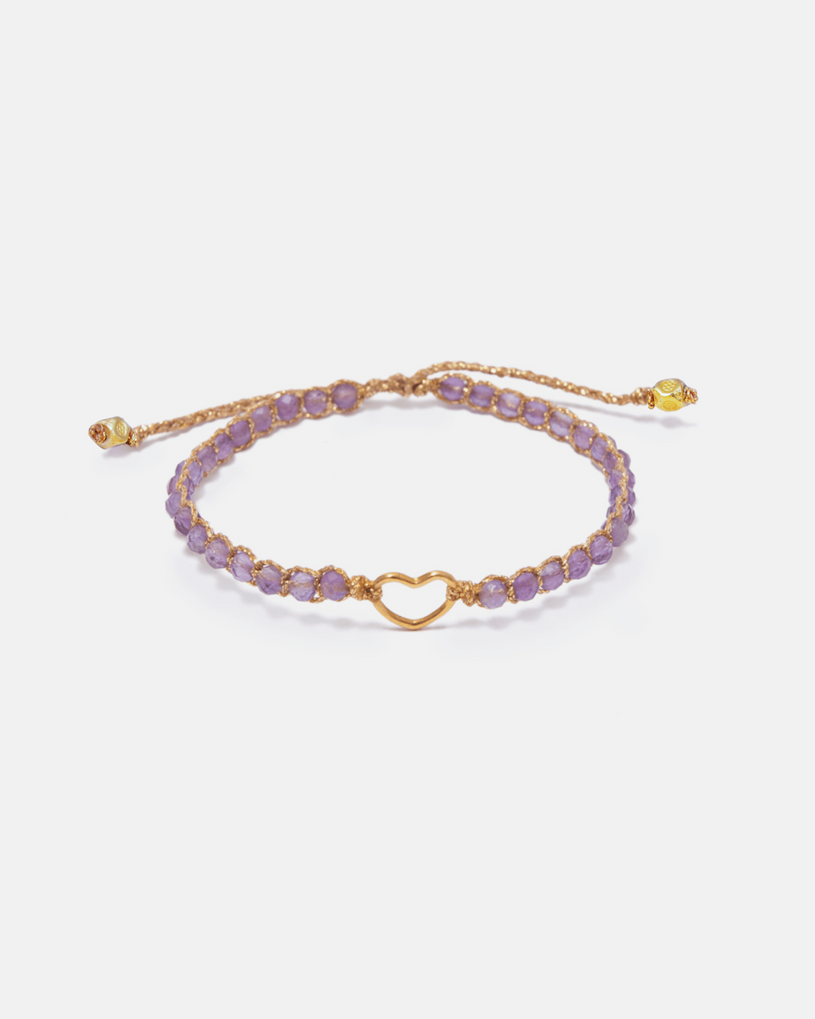 Purple beaded bracelet with gold heart charm on a white background