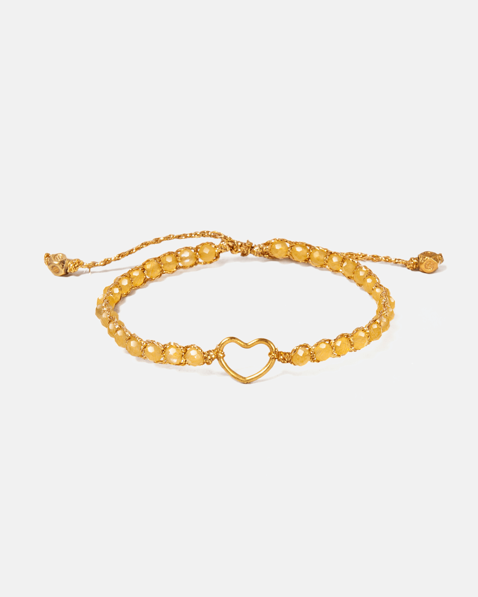 Gold and yellow beaded bracelet with a heart charm on a light gray background