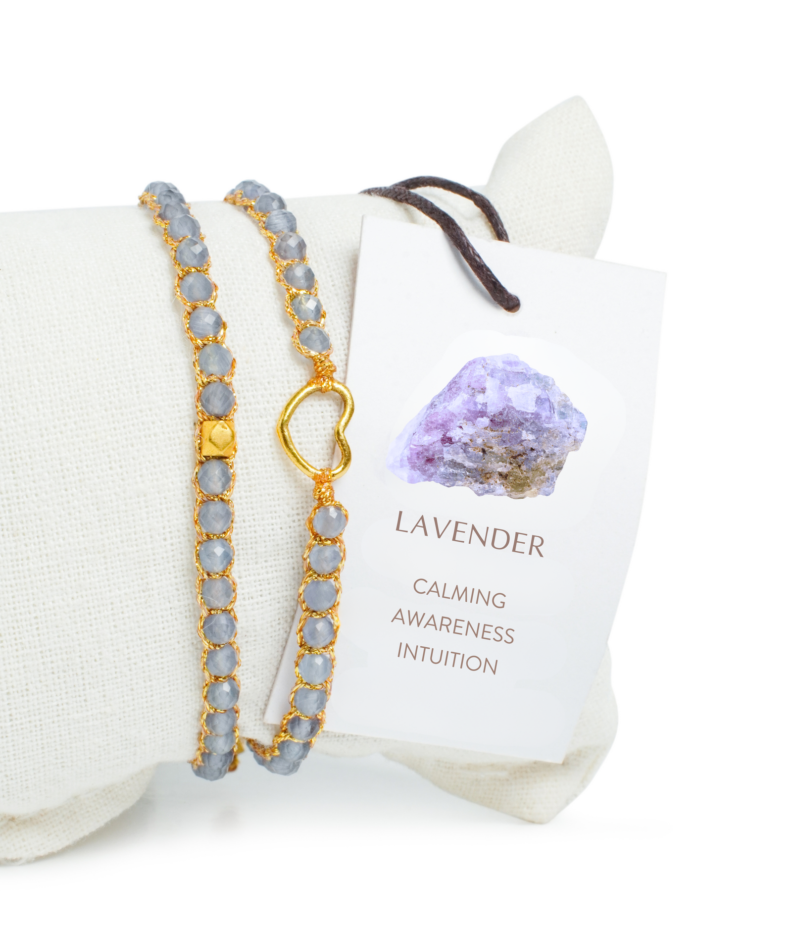 Lavender gemstone bracelet on a white pillow with an information card