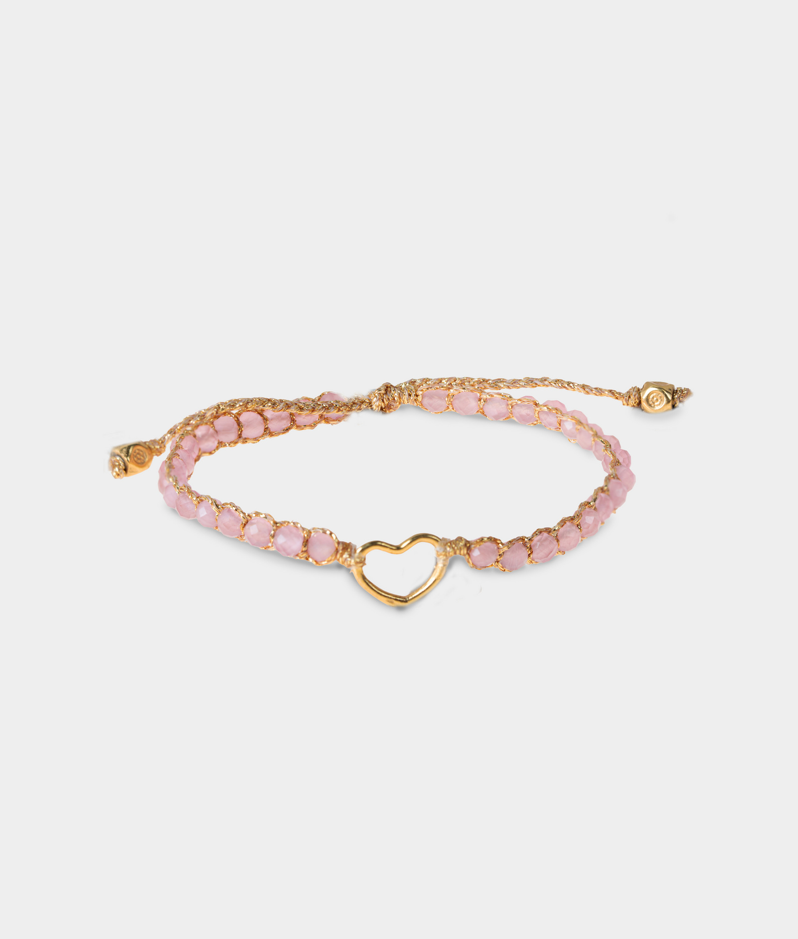 Gold bracelet with pink gemstones and a gold heart charm on a white background