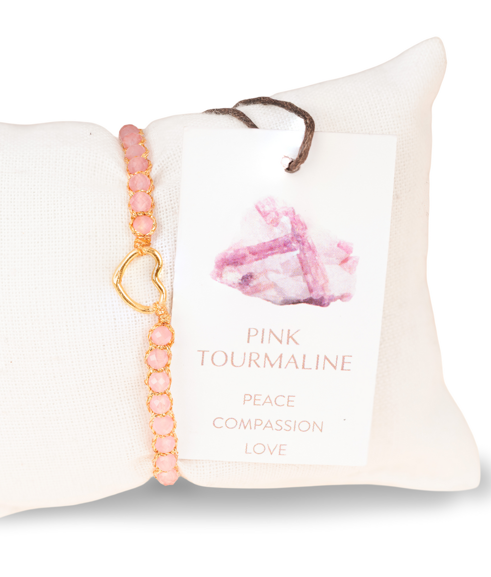 Kids pink gemstone bracelet with gold accents on a white cushion, accompanied by a card describing the stone's properties.