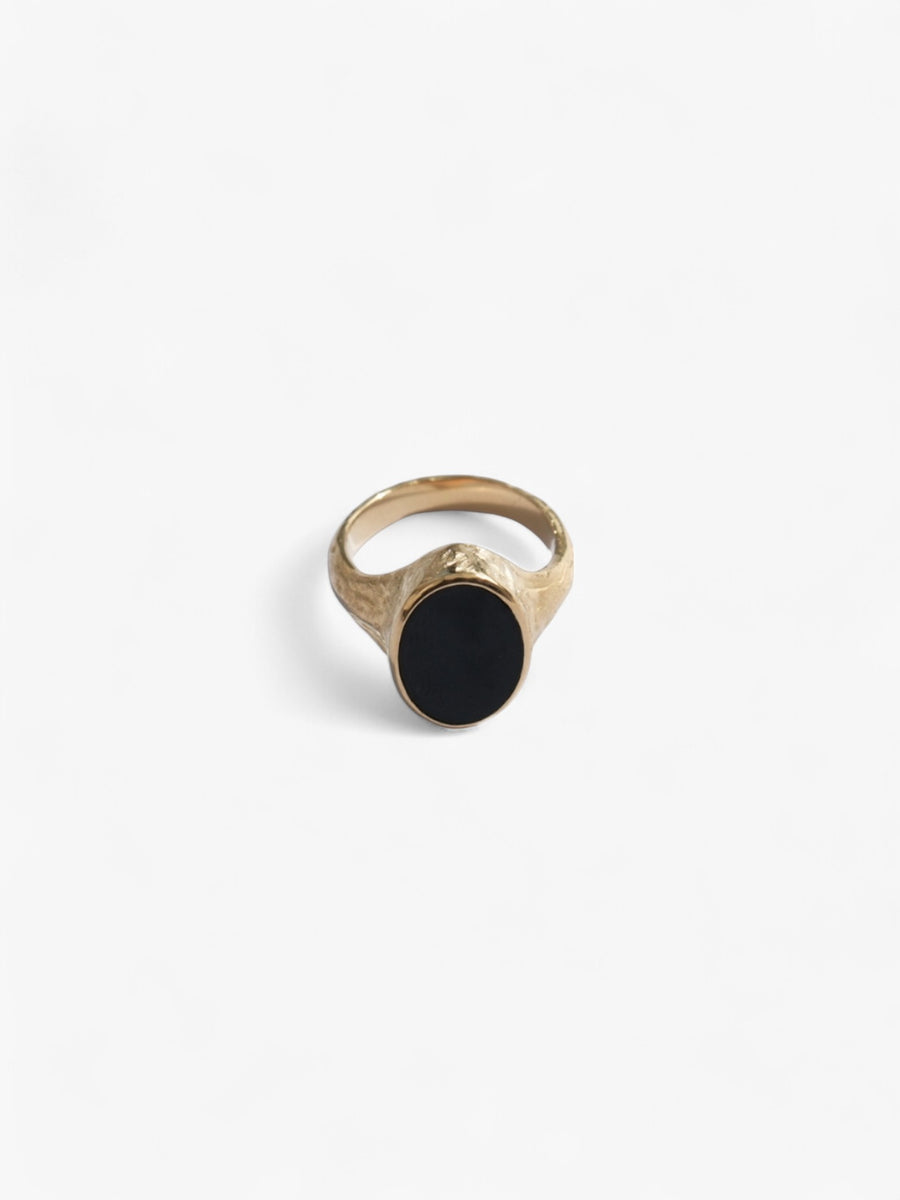 Nusands Midnight Onyx Ring in 18K Gold laying flat front on view. Oval shaped top with flat black onyx stone as a feature. 