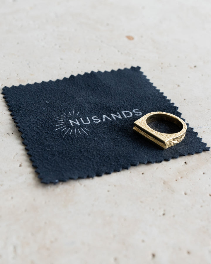 Nusands Luxe polish cloth with 18k gold line in the sand ring laying on top