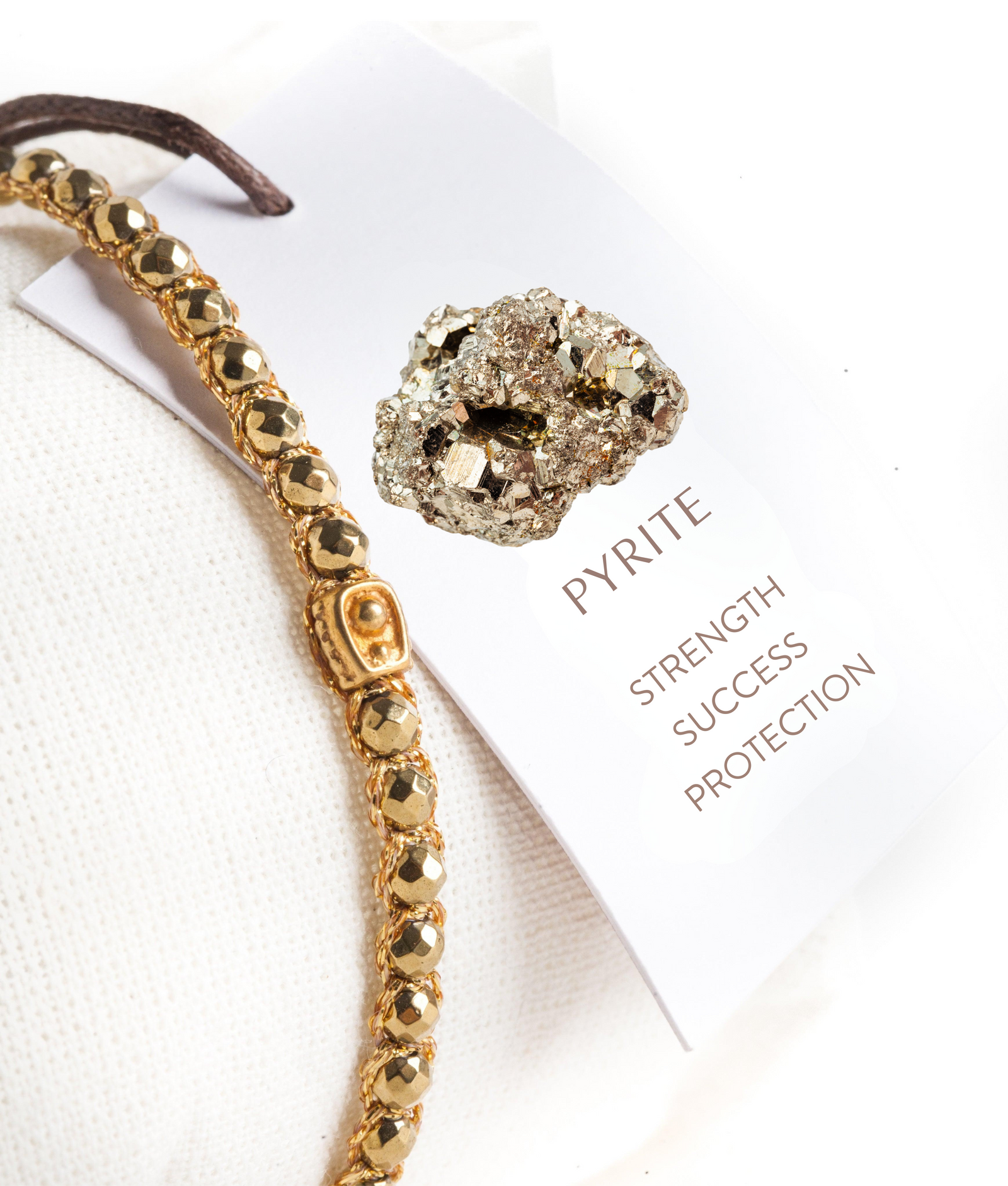 Gold bracelet and pyrite stone on a white background with healing properties