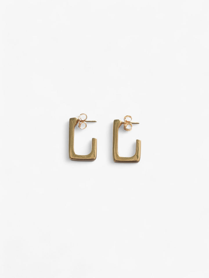 18k gold open back rectangle earrings laid on their side.