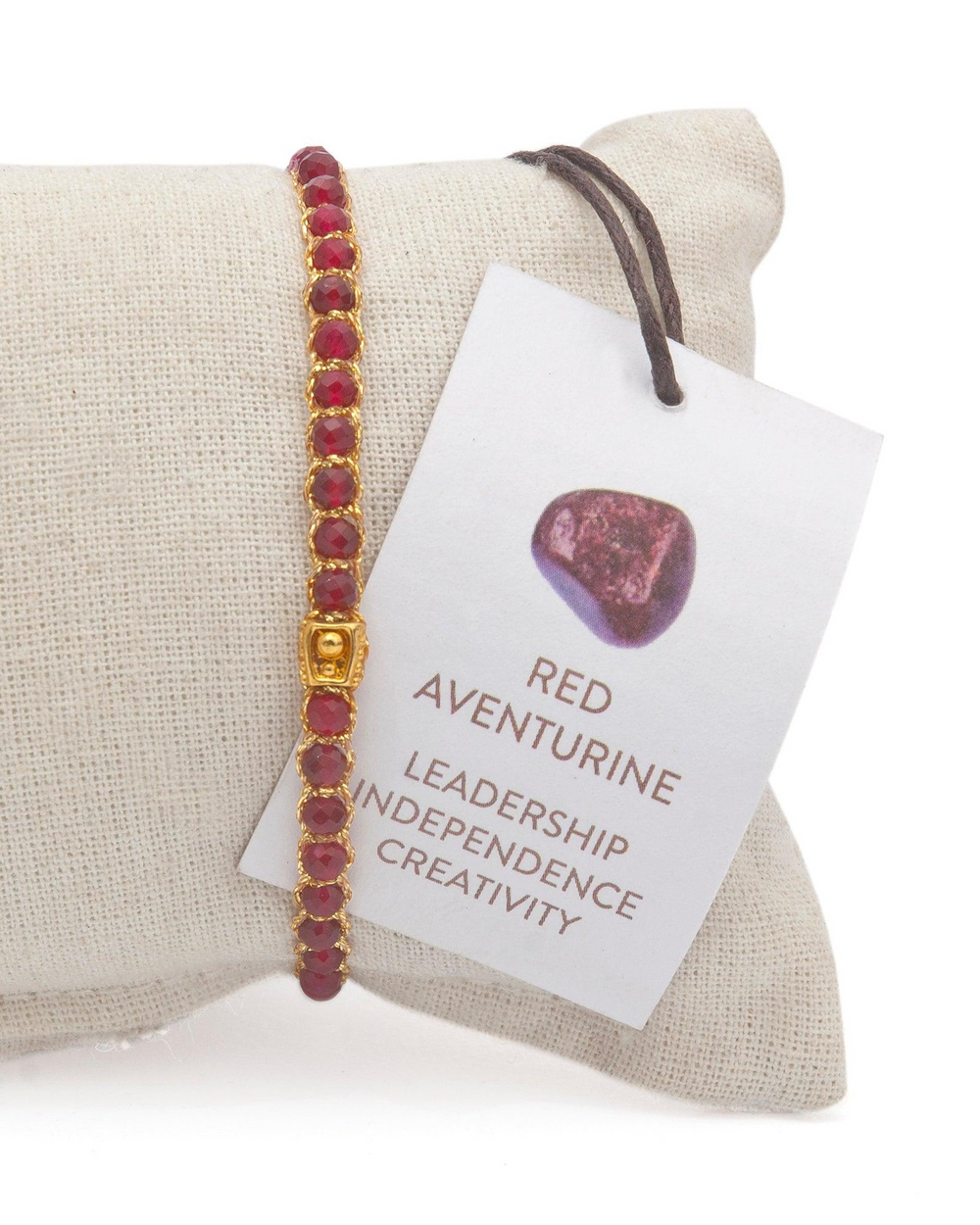 Ruby Red Gemstone Adjustable bracelet covering white cushion strung together with 18K Gold Yarn, Information tag showing.