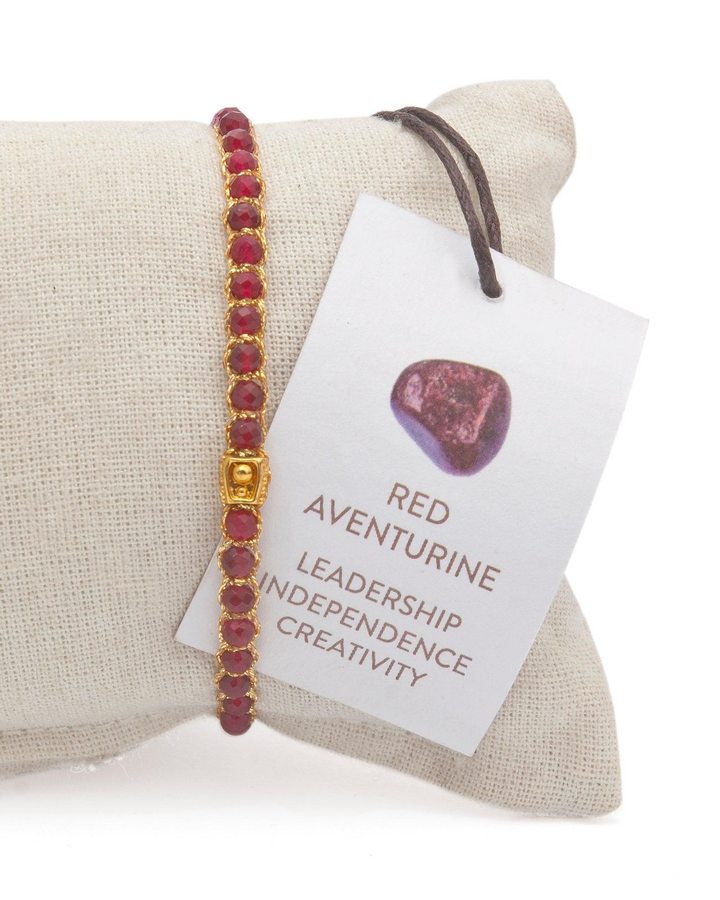 Ruby Red Gemstone Adjustable bracelet covering white cushion strung together with 18K Gold Yarn, Information tag showing.