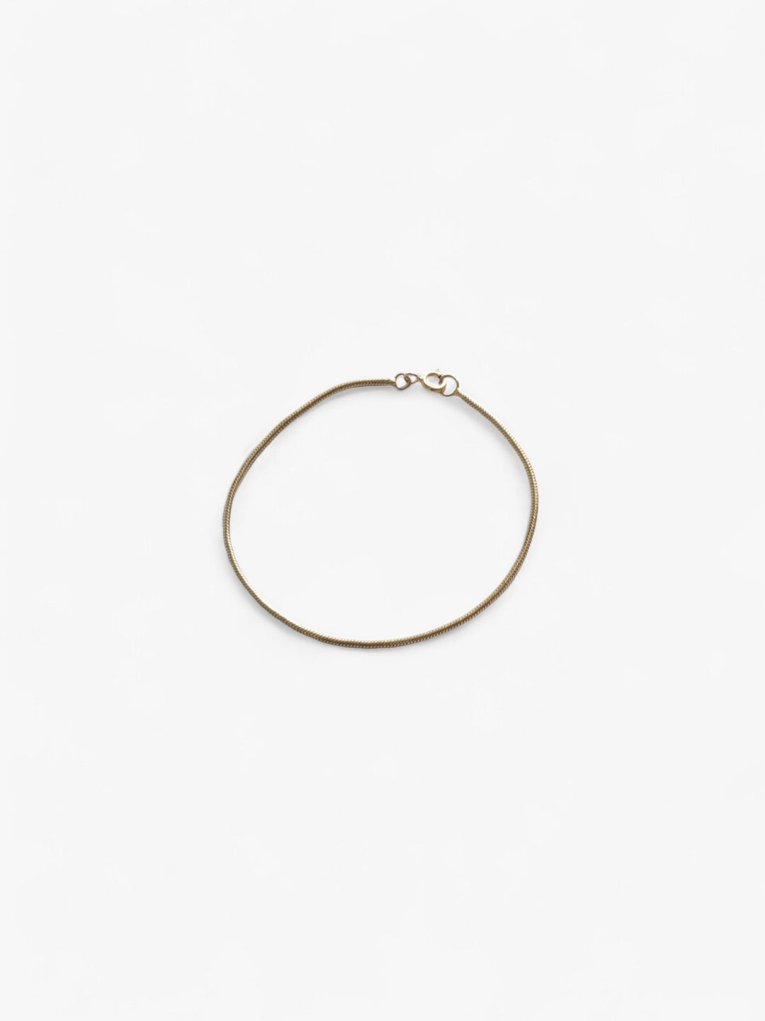 Thin 18K Gold bracelet laid flat in a circle, clasped together.