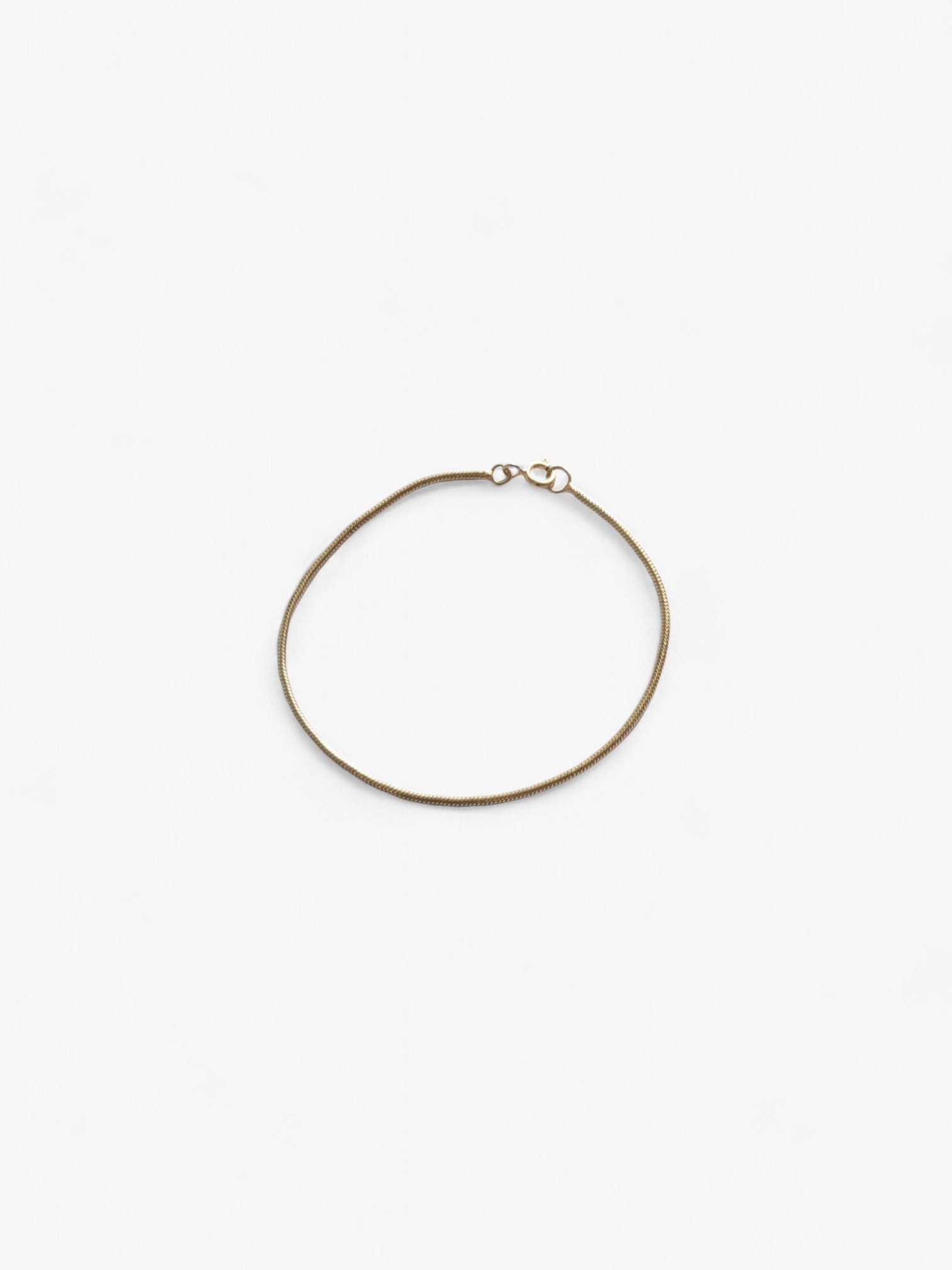 Thin 18K Gold bracelet laid flat in a circle, clasped together.