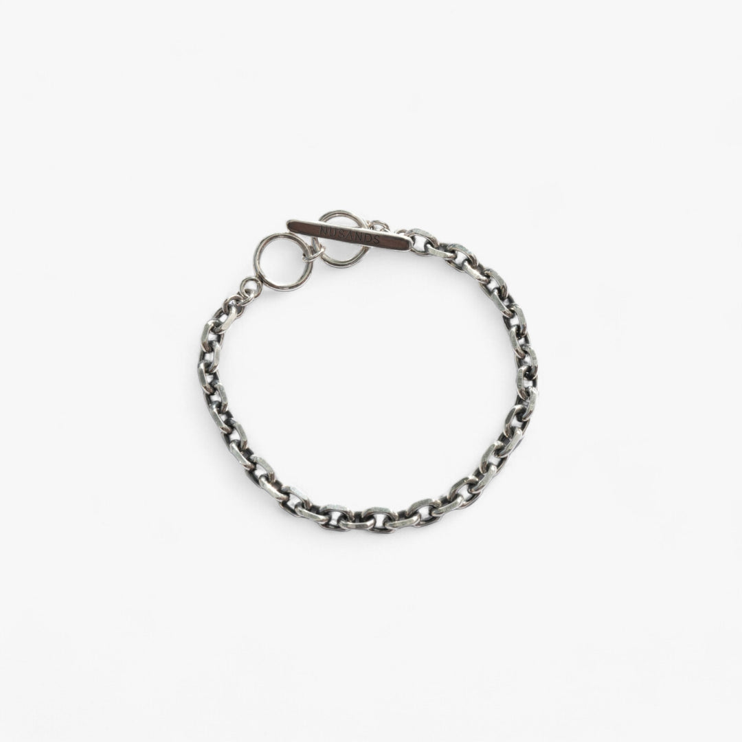 Thick sterling silver link chain with nusands logo clasp laying in a round circle