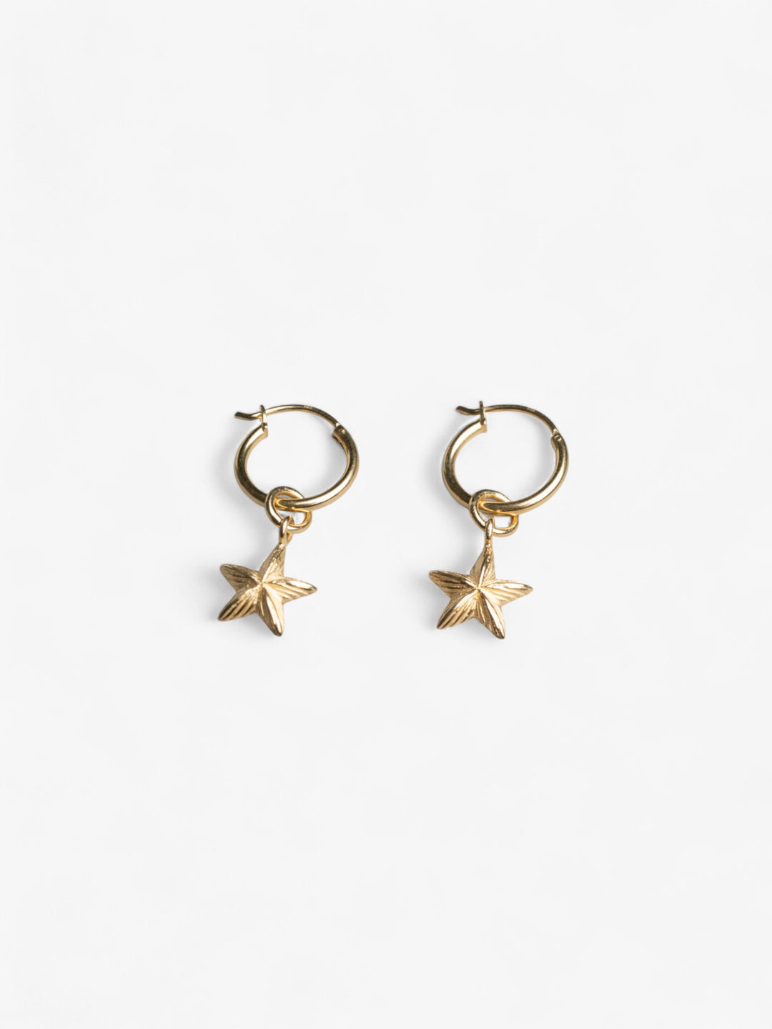 Pair of 18K Gold round hoop earrings with removable star charms laying flat next to each other.