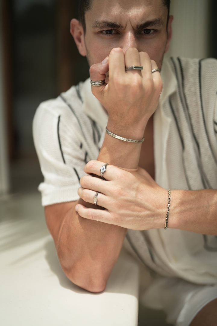 Founder of Nusands Corey Micari wearing Sterling Silver jewellery Shackled bracelet on his left wrist, mirrored signet and suns out rings on his left hand. Blade, line in the sand and stacker rings on his right hand, Striking cuff on his right wrist.