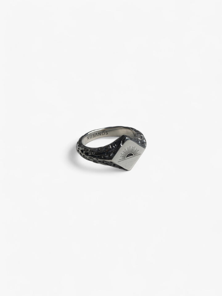 Sterling silver diamond top suns out ring with nusands signature sun engraved on the front, laying flat.