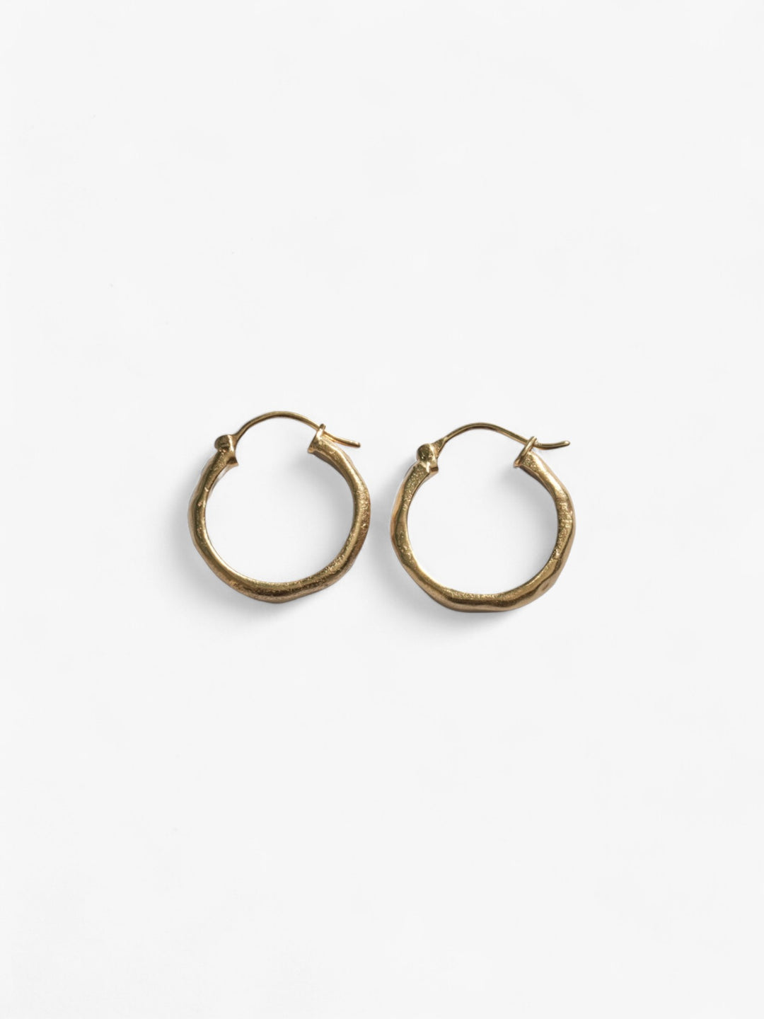 Chunky pair of 18k Gold wavy hoop earrings next to each other