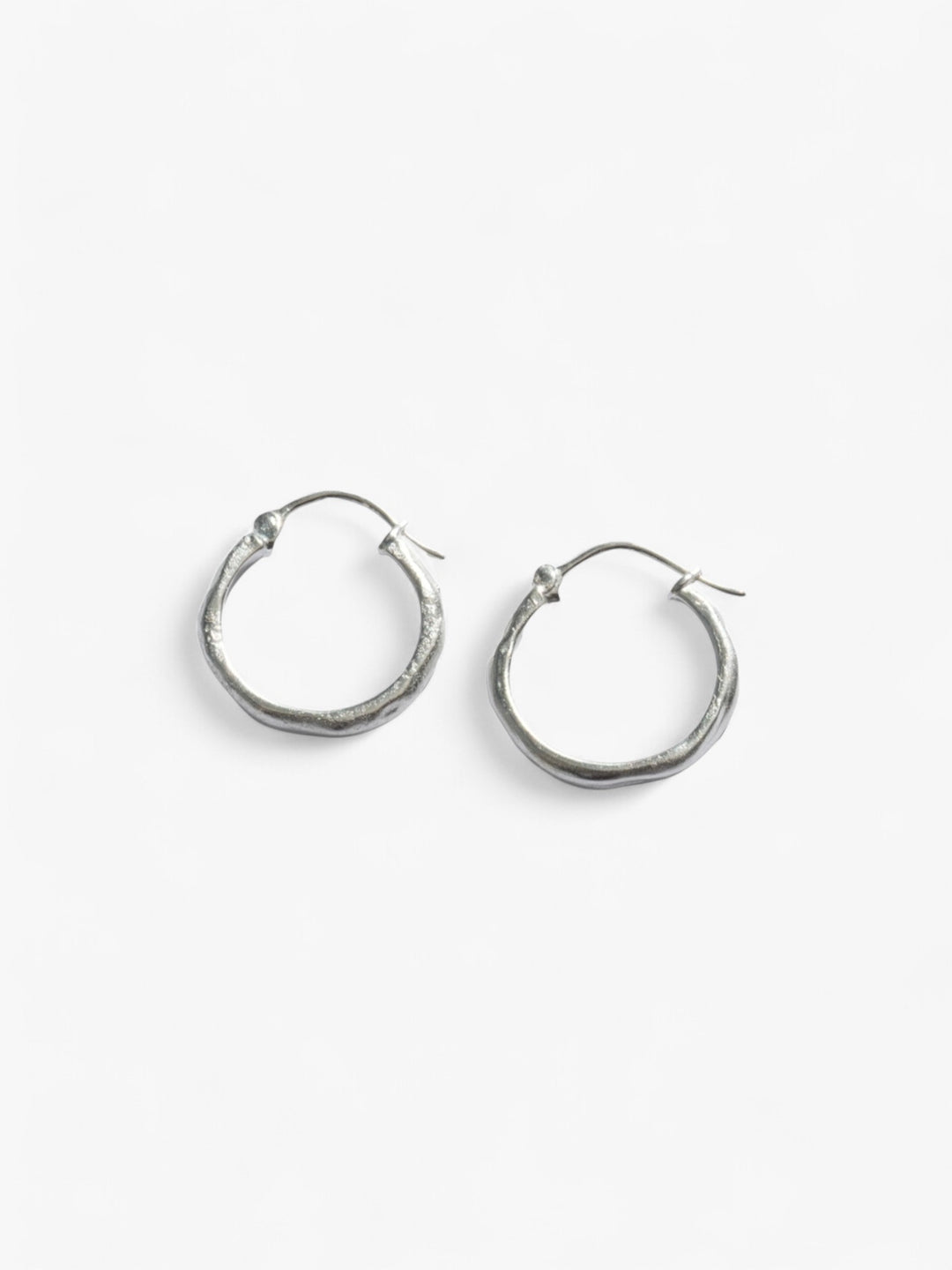 Chunky pair of sterling silver wavy hoop earrings next to each other